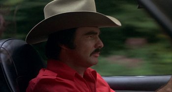 Movie still from “Smokey and the Bandit” (1977), directed by Hal Needham – A man wearing a cowboy hat sitting in the back of a car; Close Up shot, Low angle