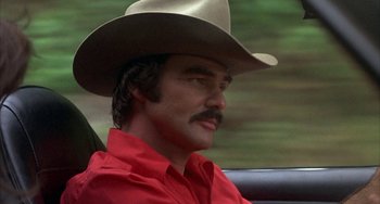 Movie still from “Smokey and the Bandit” (1977), directed by Hal Needham – A man in a cowboy hat sitting in a car; Close Up shot, Low angle
