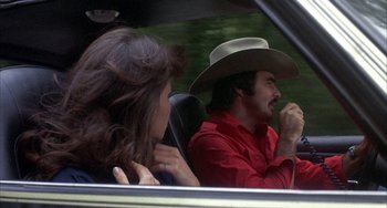 Movie still from “Smokey and the Bandit” (1977), directed by Hal Needham – A man and a woman in the back seat of a car; Medium shot, Over the shoulder angle