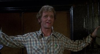 Movie still from “Smokey and the Bandit” (1977), directed by Hal Needham – A man in a plaid shirt is smiling and holding his arms out; Close Up shot, Low angle