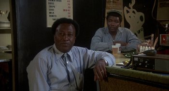 Movie still from “Smokey and the Bandit” (1977), directed by Hal Needham – A man sitting at a table in front of another man; Medium shot, Low angle