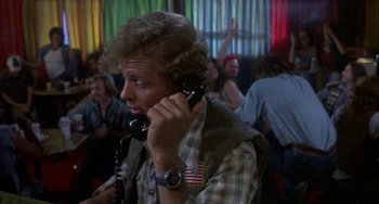Movie still from “Smokey and the Bandit” (1977), directed by Hal Needham – A man talking on a phone in front of a group of people; Close Up shot, Over the shoulder angle