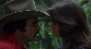 Movie still from “Smokey and the Bandit” (1977), directed by Hal Needham – A man and a woman face to face in front of trees; Close Up shot, Over the shoulder angle