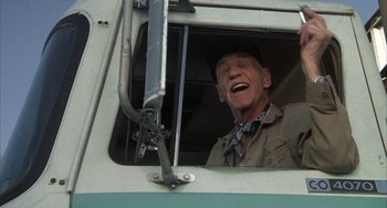 Movie still from “Smokey and the Bandit” (1977), directed by Hal Needham – An older man is smiling through the window of a bus; Medium shot, Low angle