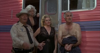 Movie still from “Smokey and the Bandit” (1977), directed by Hal Needham – A group of people standing next to each other near a trailer; Medium shot, Low angle
