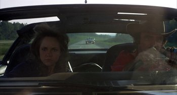 Movie still from “Smokey and the Bandit” (1977), directed by Hal Needham – A woman sitting in the back seat of a car looking out the window; Medium shot, Low angle