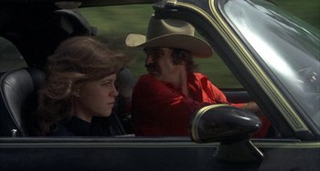 Movie still from “Smokey and the Bandit” (1977), directed by Hal Needham – A man and a woman sitting in the back seat of a car; Medium shot, Low angle