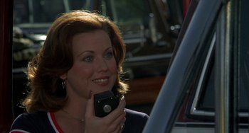 Movie still from “Smokey and the Bandit” (1977), directed by Hal Needham – A woman holding a cell phone while sitting in a car; Close Up shot, Over the shoulder angle