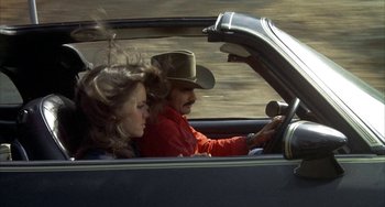Movie still from “Smokey and the Bandit” (1977), directed by Hal Needham – A man and a woman in the driver's seat of a car; Medium shot, High angle