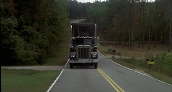 Movie still from “Smokey and the Bandit” (1977), directed by Hal Needham – A truck driving down a road near some trees; Extreme Wide shot, High angle