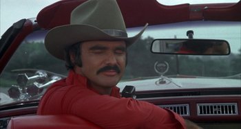 Movie still from “Smokey and the Bandit” (1977), directed by Hal Needham – A man in a cowboy hat sitting in the drivers seat of a car; Close Up shot, Over the shoulder angle
