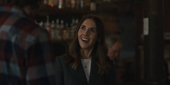 Movie still from “Somebody I Used to Know” (2023), directed by Dave Franco – A woman in a suit smiling for the camera; Close Up shot, Over the shoulder angle