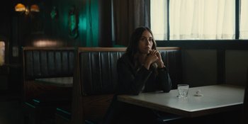 Movie still from “Somebody I Used to Know” (2023), directed by Dave Franco – A woman sitting at a table in front of a glass of water; Medium shot, High angle