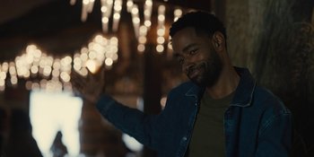 Movie still from “Somebody I Used to Know” (2023), directed by Dave Franco – A man in a denim jacket is smiling and holding his hand out; Medium shot, Over the shoulder angle