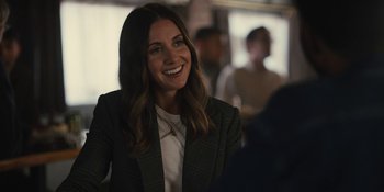 Movie still from “Somebody I Used to Know” (2023), directed by Dave Franco – A woman smiles while standing in front of a group of people; Close Up shot, Over the shoulder angle