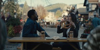Movie still from “Somebody I Used to Know” (2023), directed by Dave Franco – A man and a woman sitting at a wooden table; Medium shot, Over the shoulder angle