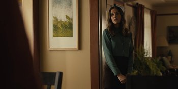 Movie still from “Somebody I Used to Know” (2023), directed by Dave Franco – A woman standing in front of a painting in a living room; Medium shot, Over the shoulder angle