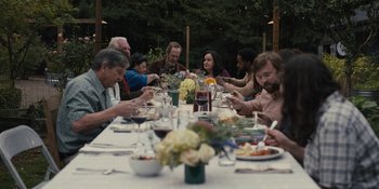 Movie still from “Somebody I Used to Know” (2023), directed by Dave Franco – A group of people sitting at a table with plates of food on it; Wide shot, High angle