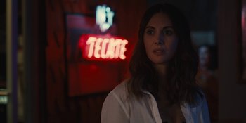 Movie still from “Somebody I Used to Know” (2023), directed by Dave Franco – A woman standing in front of a neon sign; Close Up shot, Over the shoulder angle