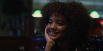 Movie still from “Somebody I Used to Know” (2023), directed by Dave Franco – A young woman with curly hair is smiling for the camera; Close Up shot, Over the shoulder angle