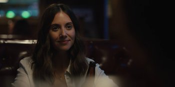 Movie still from “Somebody I Used to Know” (2023), directed by Dave Franco – A woman sitting at a table with a bottle of beer in front of her; Close Up shot, Over the shoulder angle