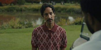 Movie still from “Somebody I Used to Know” (2023), directed by Dave Franco – A man in a red and white shirt standing in front of a body of water; Close Up shot, Over the shoulder angle