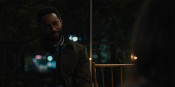 Movie still from “Somebody I Used to Know” (2023), directed by Dave Franco – A man sitting on a chair in a room at night; Medium shot, Over the shoulder angle