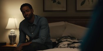 Movie still from “Somebody I Used to Know” (2023), directed by Dave Franco – A man sitting on top of a bed next to pillows; Medium shot, Over the shoulder angle