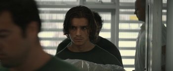 Movie still from “Son of a Gun” (2014), directed by Julius Avery – A young man with long hair and a beard; Close Up shot, Over the shoulder angle