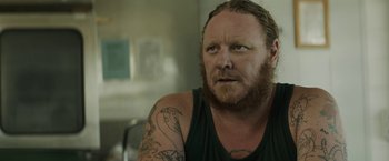 Movie still from “Son of a Gun” (2014), directed by Julius Avery – A person with a tattoo on his arm; Close Up shot, Over the shoulder angle
