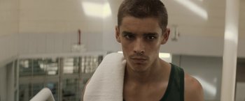 Movie still from “Son of a Gun” (2014), directed by Julius Avery – A young man with a towel around his neck; Close Up shot, Low angle