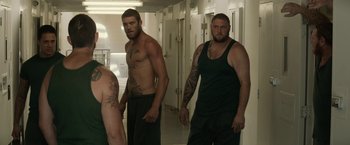 Movie still from “Son of a Gun” (2014), directed by Julius Avery – A man with tattoos standing in front of a bathroom mirror; Medium shot, Over the shoulder angle