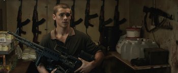 Movie still from “Son of a Gun” (2014), directed by Julius Avery – A man holding an ar - 1 5 rifle in his hands; Medium shot, Over the shoulder angle