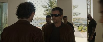 Movie still from “Son of a Gun” (2014), directed by Julius Avery – A group of men standing next to each other wearing sunglasses; Medium shot, Over the shoulder angle