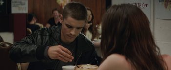 Movie still from “Son of a Gun” (2014), directed by Julius Avery – A man sitting at a table with a plate of food; Medium shot, Over the shoulder angle