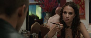 Movie still from “Son of a Gun” (2014), directed by Julius Avery – A woman sitting at a table in front of a plate; Close Up shot, Over the shoulder angle