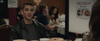 Movie still from “Son of a Gun” (2014), directed by Julius Avery – A group of people sitting at a table eating food; Medium shot, Over the shoulder angle