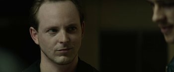 Movie still from “Son of a Gun” (2014), directed by Julius Avery – A person wearing a black shirt; Close Up shot, Over the shoulder angle