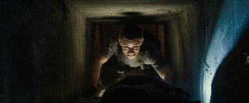 Movie still from “Son of a Gun” (2014), directed by Julius Avery – A man is looking down at the camera in a dark room; Close Up shot, Low angle