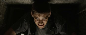 Movie still from “Son of a Gun” (2014), directed by Julius Avery – A young man is smiling for the camera; Close Up shot, Overhead angle
