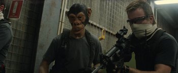 Movie still from “Son of a Gun” (2014), directed by Julius Avery – A man in a monkey mask holding a gun; Close Up shot, Over the shoulder angle