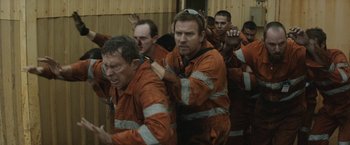 Movie still from “Son of a Gun” (2014), directed by Julius Avery – A group of men in orange work clothes; Medium shot, High angle