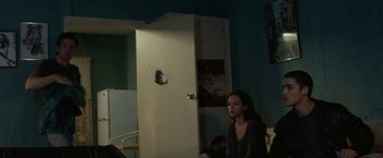 Movie still from “Son of a Gun” (2014), directed by Julius Avery – A woman standing in front of an open door; Medium shot, Over the shoulder angle