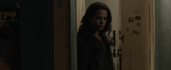 Movie still from “Son of a Gun” (2014), directed by Julius Avery – A woman standing in front of a door looking at the camera; Medium shot, Over the shoulder angle