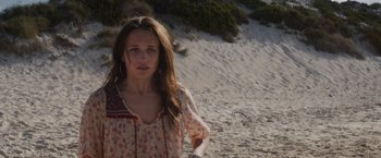Movie still from “Son of a Gun” (2014), directed by Julius Avery – A woman standing on top of a sandy beach; Close Up shot, High angle
