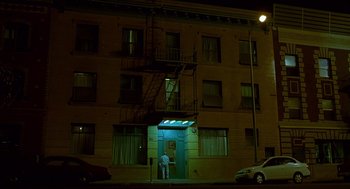 Movie still from “One Hour Photo” (2002), directed by Mark Romanek – A man standing in front of a building at night; Extreme Wide shot, Low angle