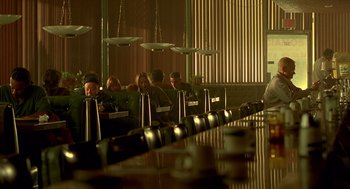 Movie still from “One Hour Photo” (2002), directed by Mark Romanek – A group of people sitting at a long table in a restaurant; Wide shot, High angle