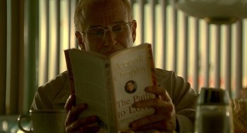 Movie still from “One Hour Photo” (2002), directed by Mark Romanek – An older man reading a book in front of a window; Close Up shot, High angle