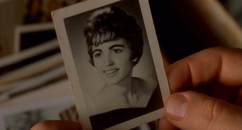 Movie still from “One Hour Photo” (2002), directed by Mark Romanek – An old photo of a woman's face is held up; Extreme Close Up shot, Overhead angle