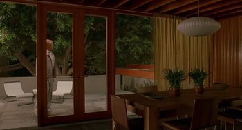 Movie still from “One Hour Photo” (2002), directed by Mark Romanek – A table and chairs in a room with a patio door open; Wide shot, High angle